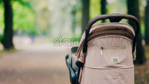 A beige baby stroller parked on a forest path in a park - Starpik Stock