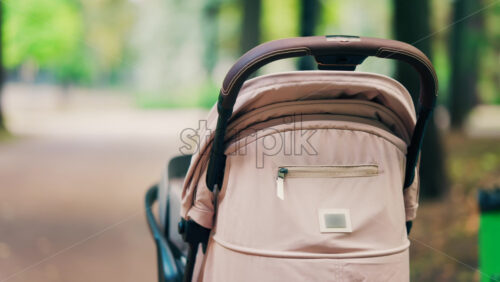 A beige baby stroller parked on a forest path in a park - Starpik Stock