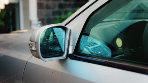 A man washing a silver car window with a cleaning brush, removing soap and dirt - Starpik Stock