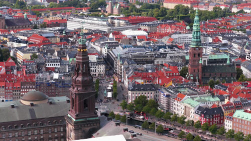 Aerial drone view of Christiansborg Palace tower and the green spire of Nikolaj Church surrounded by red rooftops in Copenhagen, Denmark - Starpik Stock