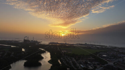Aerial drone view of Copenhagen, Denmark at sunset with glowing skies, wind turbines in the background - Starpik Stock