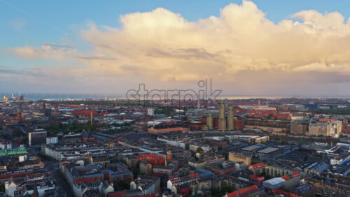 Aerial drone view of Copenhagen, Denmark with historic towers, modern buildings, and red rooftops under a bright morning sky - Starpik Stock
