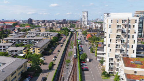 Aerial drone view of Copenhagen Metro line, with a train traveling through residential neighborhoods near Amager in Denmark - Starpik Stock