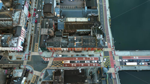 Aerial drone view of Cork’s River Lee and its iconic bridges flowing through the city center, with dense architecture and traffic movement - Starpik Stock