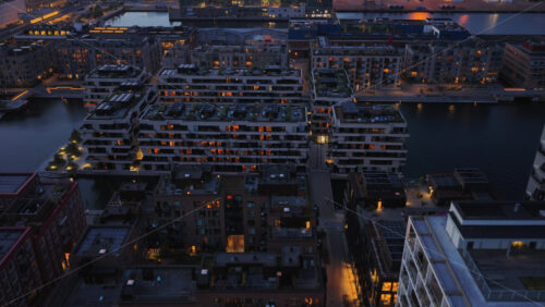 Aerial drone view of Orestad’s residential district with illuminated modern apartment blocks at night in Copenhagen, Denmark - Starpik Stock