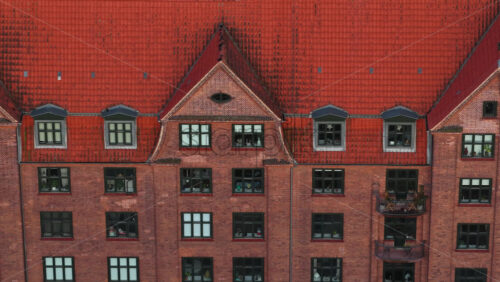 Aerial drone view of a traditional red-brick residential building in Amagerbro, Copenhagen, Denmark, with steep tiled roofs and Scandinavian architecture - Starpik Stock