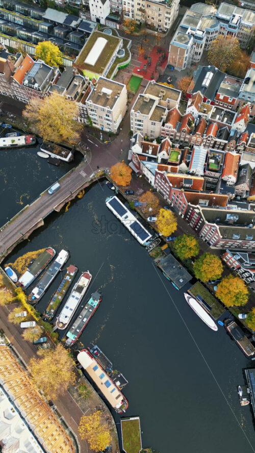 Aerial drone view of buildings surrounding a tree-lined canal in Amsterdam, Netherlands in daylight. Vertical - Starpik Stock