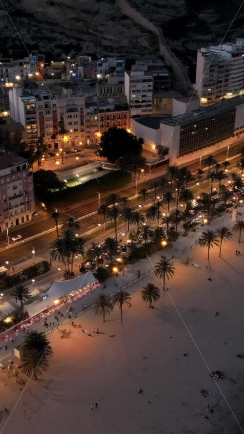 Aerial drone view of cars moving along the coastline in Alicante, Spain in the evening. Vertical - Starpik Stock