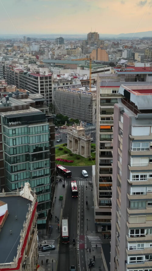 Aerial drone view of cars moving on the streets between the buildings, near Porta De La Mar in Valencia, Spain in daylight. Vertical - Starpik Stock