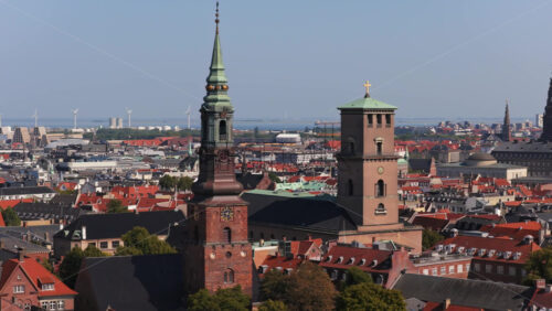 Aerial drone view of historic church towers including the spire of Nikolaj Kunsthal and the tower of Church of Our Lady in Copenhagen, Denmark - Starpik Stock