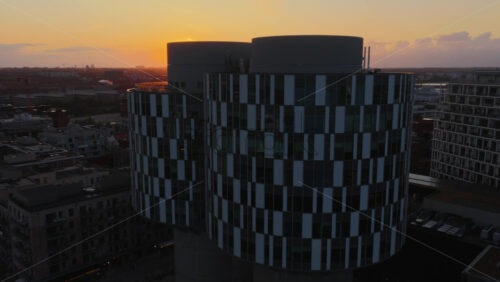 Aerial drone view of modern round CPH Towers building in Orestad, Copenhagen, Denmark at sunset - Starpik Stock