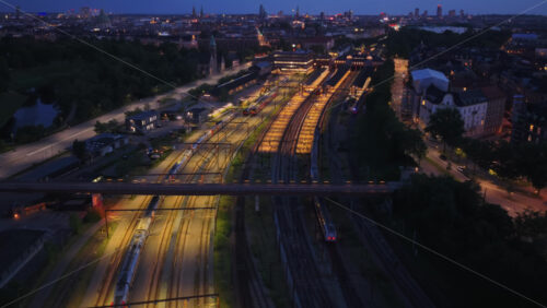 Aerial drone view of multiple illuminated railway tracks and trains in Copenhagen, Denmark - Starpik Stock
