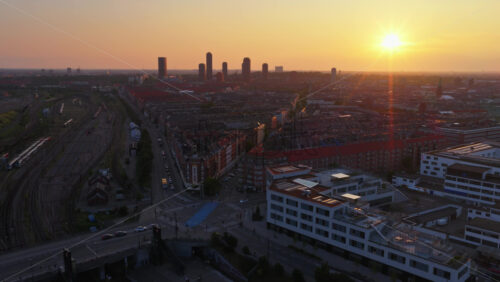 Aerial drone view of railway lines and rooftops in Vesterbro with the sun setting behind modern towers in Copenhagen, Denmark - Starpik Stock