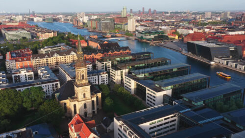 Aerial drone view of the Christians Kirke church in Copenhagen, Denmark with the city waterfront, canals, and modern architecture in the background - Starpik Stock