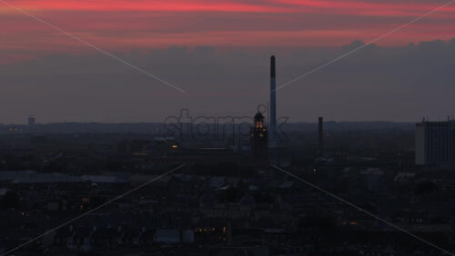 Aerial drone view of the Karlsberg district at dusk with a historic brewery tower and tall chimney standing out against a dramatic red-orange sunset sky in Copenhagen, Denmark - Starpik Stock