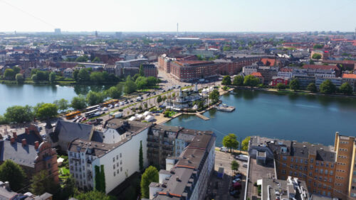 Aerial drone view of the Lakes in Copenhagen, Denmark, showing the urban waterfront, historic apartment buildings, tree-lined streets, and city infrastructure - Starpik Stock