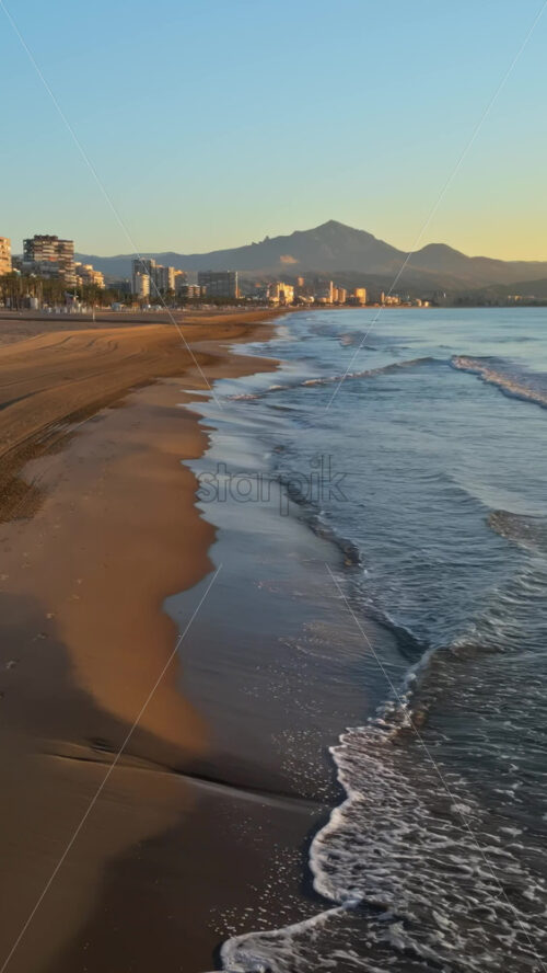 Aerial drone view of the Mediterranean Sea and the city of Alicante, Spain at sunset. Vertical - Starpik Stock