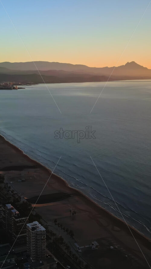Aerial drone view of the Mediterranean Sea and the city of Alicante, Spain at sunset. Vertical - Starpik Stock