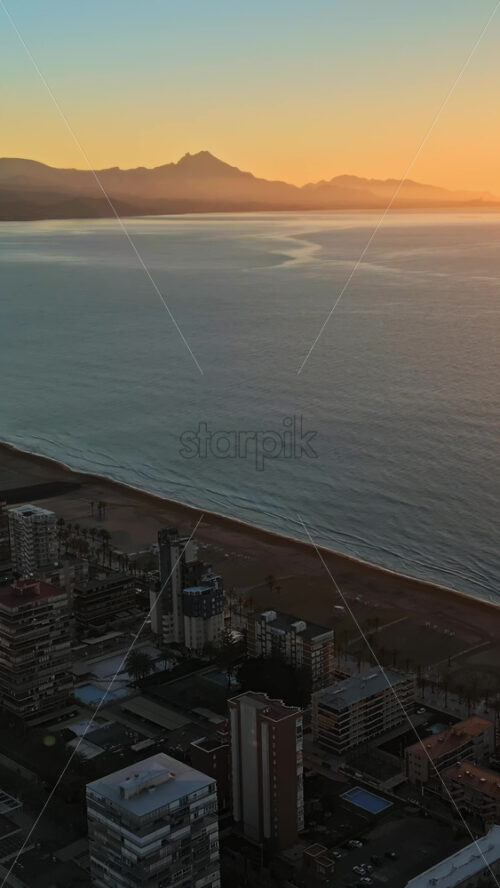 Aerial drone view of the Mediterranean Sea and the city of Alicante, Spain at sunset. Vertical - Starpik Stock