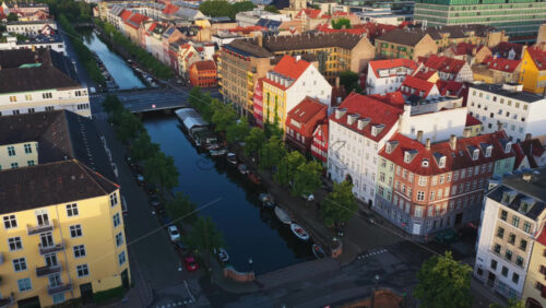 Aerial drone view of the Nyhavn Canal lined with colourful historic buildings, red rooftops, and moored boats - Starpik Stock