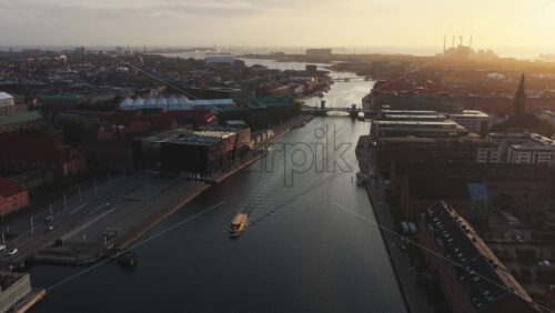 Aerial drone view of the Nyhavn canal and cityscape during golden hour, with boats and modern buildings along the waterfront in Copenhagen, Denmark - Starpik Stock