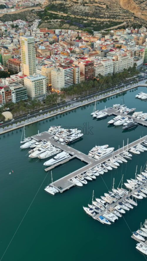 Aerial drone view of the Port of Alicante and the buildings in the city in the evening. Vertical - Starpik Stock
