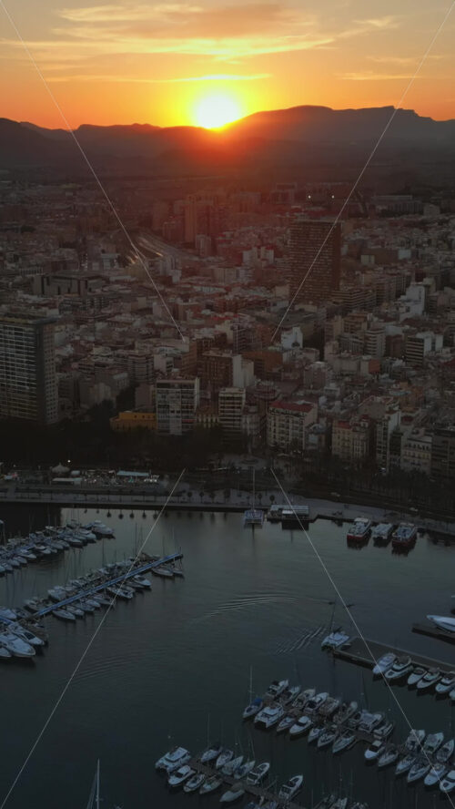 Aerial drone view of the Port of Alicante and the buildings in the city in the evening. Vertical - Starpik Stock