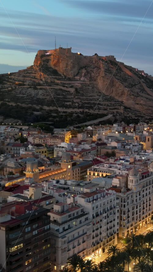 Aerial drone view of the Santa Barbara Castle on the coast of Alicante, Spain at sunset. Vertical - Starpik Stock