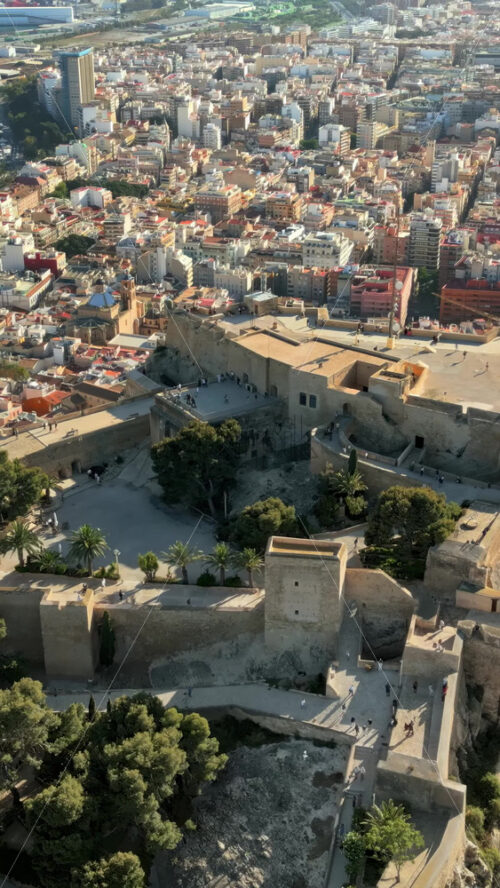 Aerial drone view of the Santa Barbara Castle on the coast of Alicante, Spain with the city and the sea on the background. Vertical - Starpik Stock