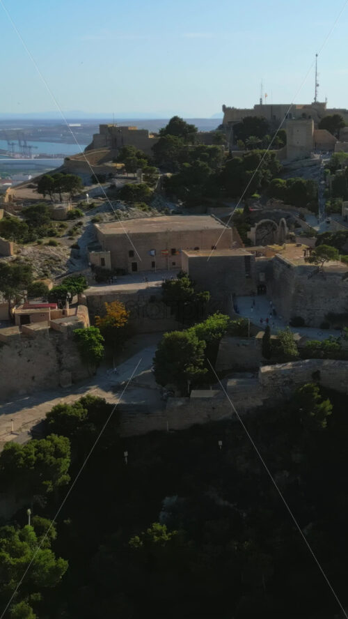 Aerial drone view of the Santa Barbara Castle on the coast of Alicante, Spain with the city and the sea on the background. Vertical - Starpik Stock