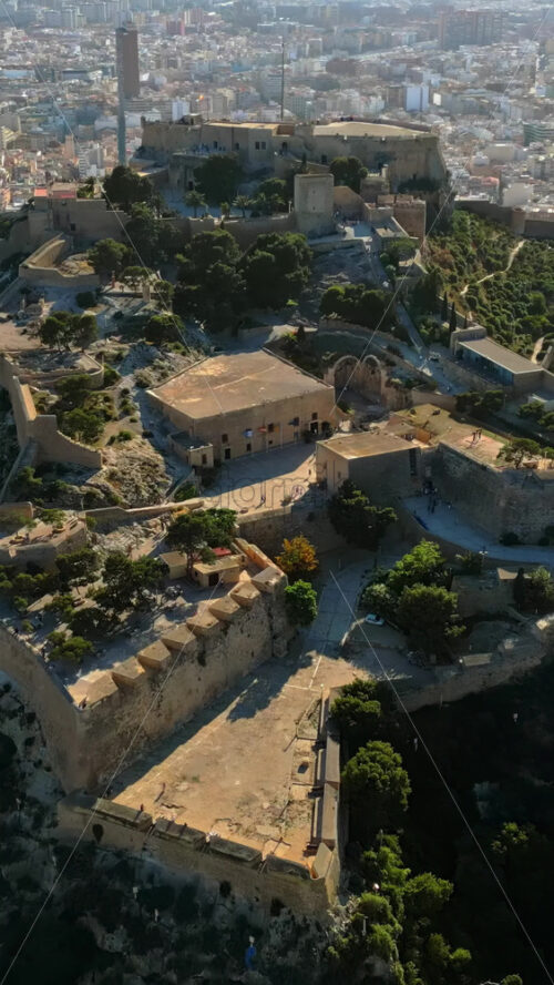 Aerial drone view of the Santa Barbara Castle on the coast of Alicante, Spain with the city on the background. Vertical - Starpik Stock
