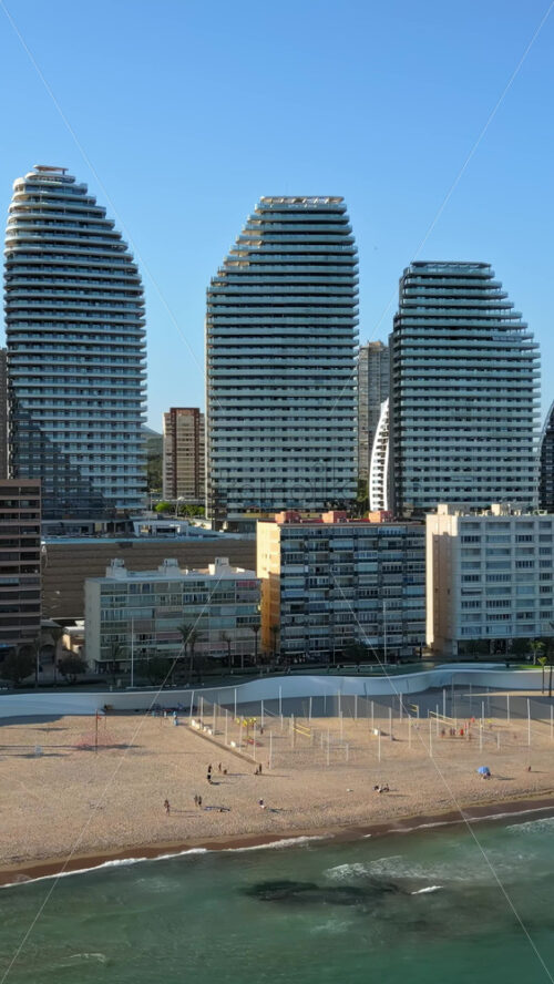 Aerial drone view of the buildings along the coastline and the sea in Benidorm, Spain in daylight. Vertical - Starpik Stock