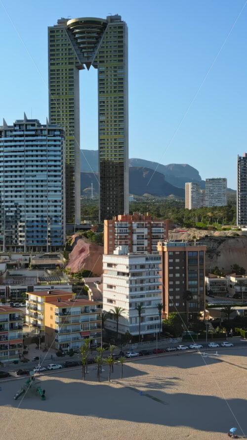 Aerial drone view of the buildings along the coastline and the sea in Benidorm, Spain in daylight. Vertical - Starpik Stock