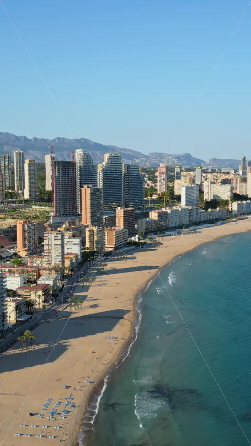 Aerial drone view of the buildings along the coastline and the sea in Benidorm, Spain in daylight. Vertical - Starpik Stock