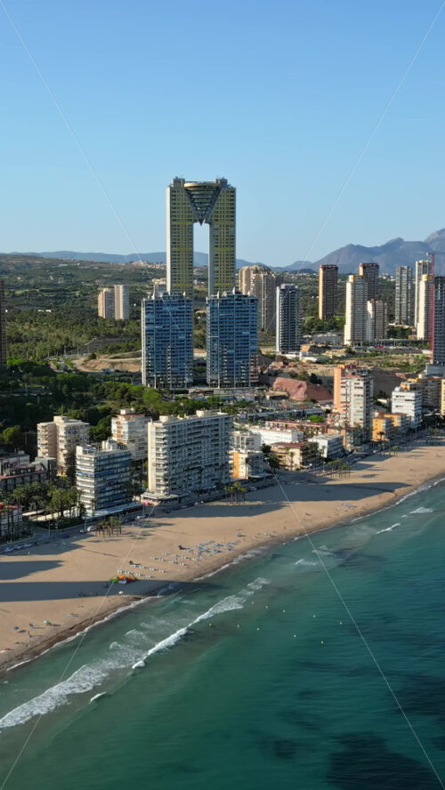 Aerial drone view of the buildings along the coastline and the sea in Benidorm, Spain in daylight. Vertical - Starpik Stock