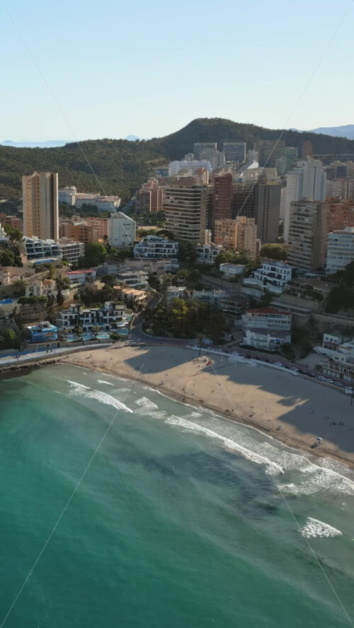 Aerial drone view of the buildings along the coastline and the sea in Benidorm, Spain in daylight. Vertical - Starpik Stock