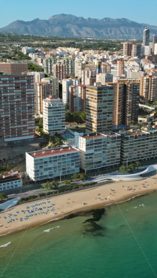 Aerial drone view of the buildings along the coastline and the sea in Benidorm, Spain in daylight. Vertical - Starpik Stock