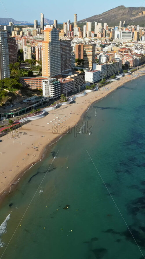 Aerial drone view of the buildings along the coastline and the sea in Benidorm, Spain in daylight. Vertical - Starpik Stock