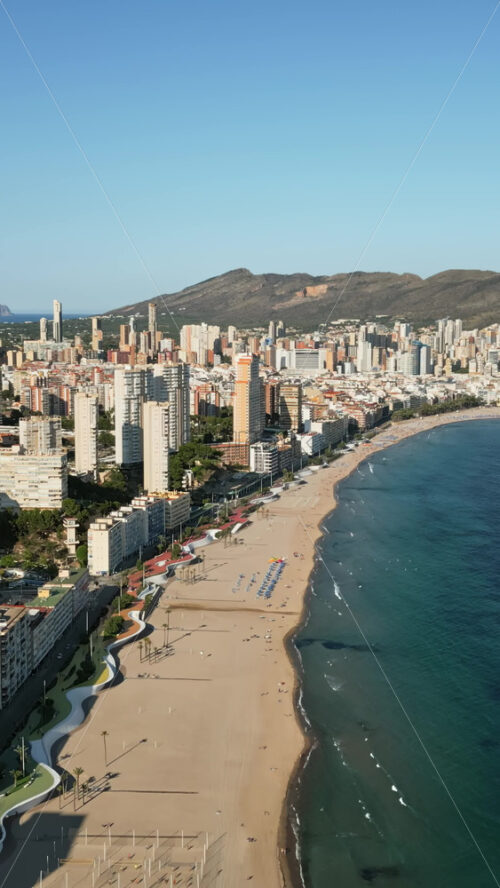 Aerial drone view of the buildings along the coastline and the sea in Benidorm, Spain in daylight. Vertical - Starpik Stock