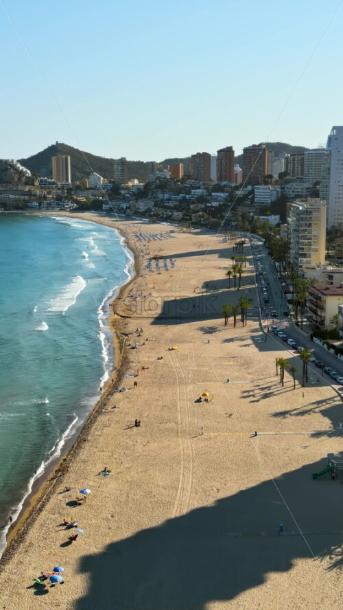 Aerial drone view of the buildings along the coastline and the sea in Benidorm, Spain in daylight. Vertical - Starpik Stock