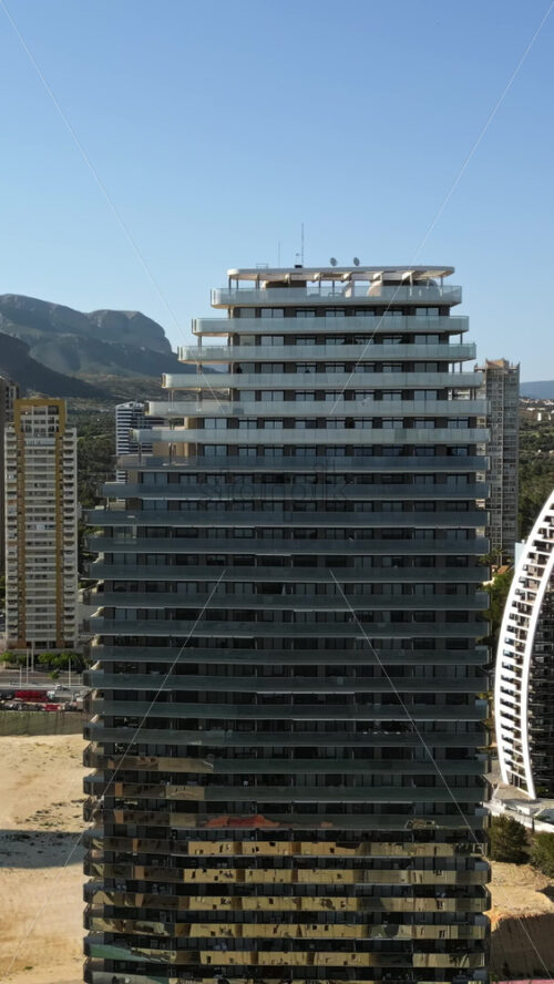 Aerial drone view of the buildings along the coastline in Benidorm, Spain in daylight. Vertical - Starpik Stock