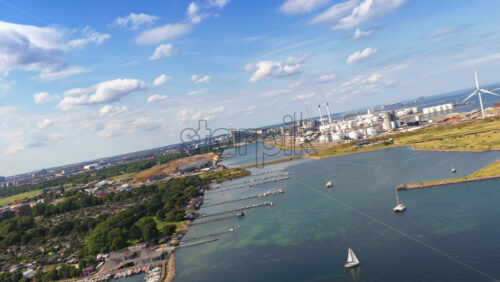 Aerial drone view of the coastline near Amager Strandpark, with sailboats in the water and CopenHill visible in the distance in Copenhagen, Denmark - Starpik Stock