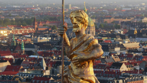 Aerial drone view of the golden statue atop a sphere on the Church of Our Saviour overlooking the Copenhagen skyline, with Frederik’s Church dome in the background in Denmark - Starpik Stock
