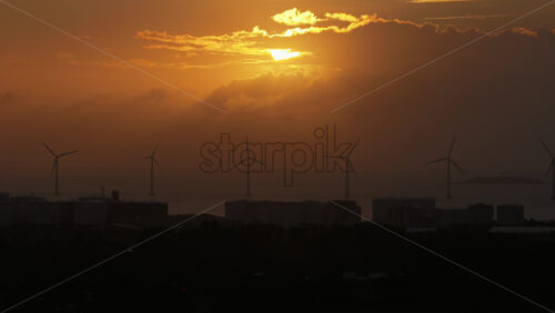 Aerial drone view of the golden sun over the Danish coast, casting light on offshore wind turbines - Starpik Stock