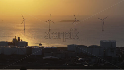 Aerial drone view of the golden sun over the Danish coast, casting light on offshore wind turbines. Copenhagen, Denmark - Starpik Stock