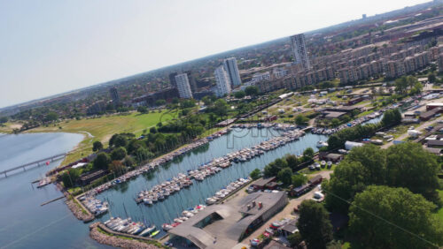 Aerial drone view of the marina filled with sailboats, surrounded by residential blocks and the green coast in Copenhagen, Denmark - Starpik Stock