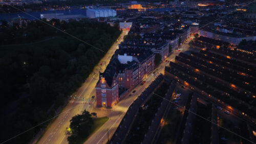 Aerial drone view of the triangular building lit up at night along Oster Voldgade, Copenhagen, Denmark - Starpik Stock