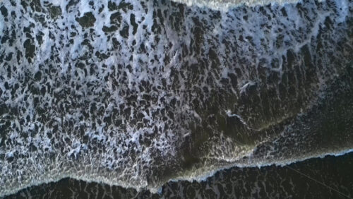 Aerial drone view of waves crashing on the beach in The Hague, Netherlands - Starpik Stock