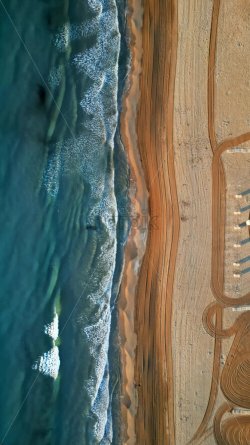 Aerial drone view of waves hitting the shore on the beach in Alicante, Spain. Vertical - Starpik Stock
