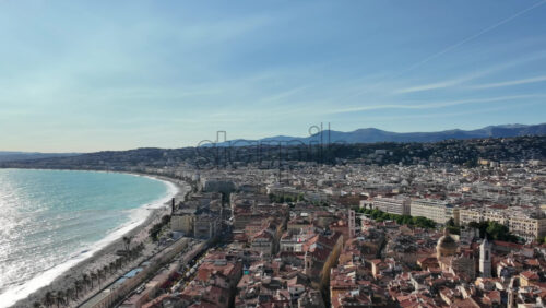 Aerial view of Nice, France with red tiled rooftops, sweeping bay, and mountain backdrop - Starpik Stock